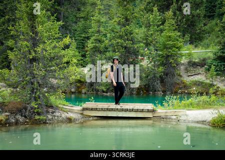 Wanderer auf einer kleinen Brücke über den lebendigen blauen Gletscherbach im Wald. Stockfoto