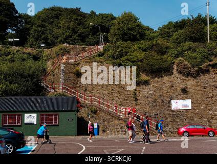 COBH, IRLAND - 15. August 2025: Historische Fußgängerbrücke und Steintreppe verbinden den oberen Cobh mit dem Hafen, der über die Bahnstrecke in der Nähe der cruis überspannt Stockfoto