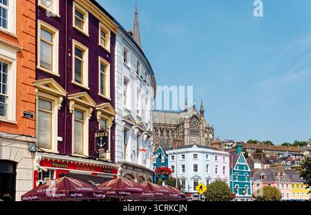 COBH, IRLAND - 15. August 2025: Eine Reihe von bunt bemalten georgianischen Gebäuden säumt den historischen Hafen von Cobh, ein beliebter Zwischenstopp für Touristen und Cru Stockfoto