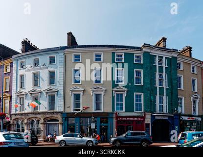 COBH, IRLAND - 15. August 2025: Eine Reihe von bunt bemalten georgianischen Gebäuden säumt den historischen Hafen von Cobh, ein beliebter Zwischenstopp für Touristen und Cru Stockfoto