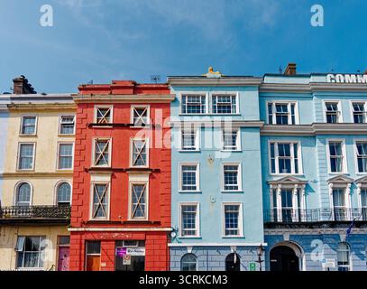 COBH, IRLAND - 15. August 2025: Eine Reihe von bunt bemalten georgianischen Gebäuden säumt den historischen Hafen von Cobh, ein beliebter Zwischenstopp für Touristen und Cru Stockfoto