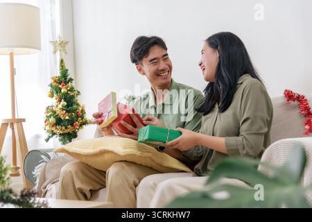Weihnachten, glückliches Paar zeigt Liebe im Urlaub und öffnet Geschenke in der Nähe von festlichem Baum in gemütlichem Haus Stockfoto