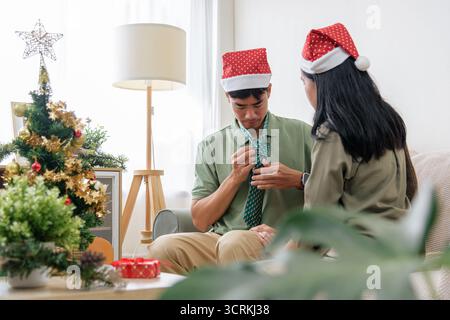 Weihnachtsfeier, glückliche Paare lieben es, sich auf die Winterferien vorzubereiten, indem sie eine Krawatte in der Nähe binden Stockfoto