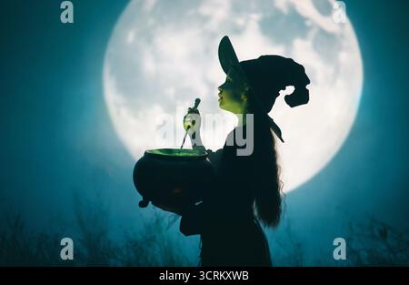Mädchen in Hexenkostümen für Halloween. Junge, der auf Vollmond-Hintergrund steht. Stockfoto