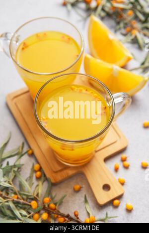 Sanddorn Beeren- und Orangenscheiben, die ein gesundes Kräutergetränk in klaren Tassen schaffen Stockfoto