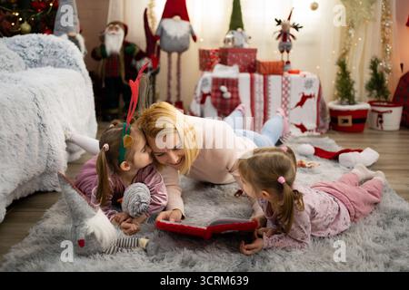 Mutter liest ihren Töchtern eine Weihnachtsgeschichte vor Stockfoto