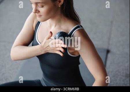 Fokussierte Frau, die während des Workouts einen Massageball auf der Schulter verwendet. Fitness- und Gesundheitskonzept Stockfoto