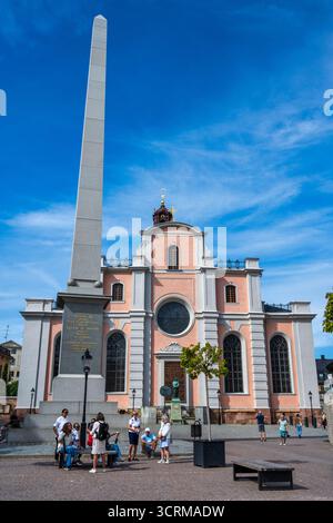 Gustav III Obelisk auf Slottsbacken, mit der Stockholmer Kathedrale (Storkyrkan) im Hintergrund in der Stockholmer Altstadt (Gamla Stan) in Schweden, Nordeuropa Stockfoto