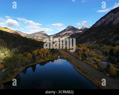 Aerial view of the serene still lake reflecting the clear blue sky, nestled amidst the vibrant autumn foliage and towering mountains, Marble, Colorado, United States. Stockfoto