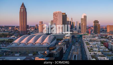 Aus der Vogelperspektive auf die Messe Frankfurt und eine Gruppe von Wolkenkratzern im warmen Glanz der untergehenden Sonne, Frankfurt am Main, Hessen, Deutschland. Stockfoto
