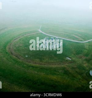 Aus der Vogelperspektive der alten, verwitterten Steine von Stonehenge stehen stark vor der weichen, grünen Landschaft unter einer Decke aus ätherischem Nebel, Salisbury, England, Vereinigtes Königreich. Stockfoto