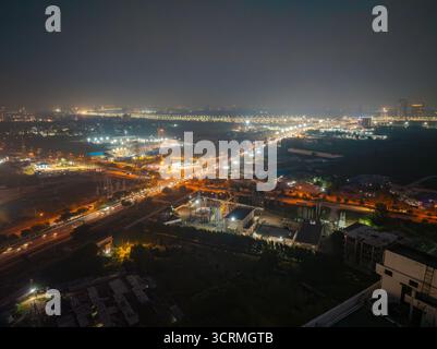 Aus der Vogelperspektive funkeln die Lichter der Stadt wie verstreute Juwelen in der Landschaft, die Straßen und Gebäude in der Nacht beleuchten, Gurugram, Haryana, Stockfoto