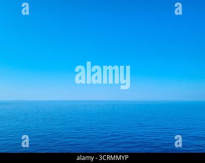 Ruhiges blaues Ägäis mit klarem Sommerhimmel und fernem Horizont, friedlicher mediterraner Meereslandschaft im Hintergrund, ideal für Reisen, Entspannung und na Stockfoto