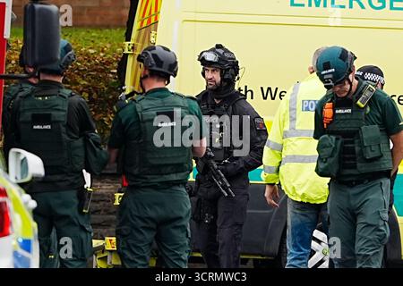Ein bewaffneter Polizist mit Mitgliedern des Rettungsdienstes am Ort eines Vorfalls in der Heaton Park Hebrew Congregation Synagoge in Crumpsall, Manchester, wo die Polizei einen Verdächtigen erschossen hat, nachdem mehrere Menschen erstochen wurden und ein Auto auf Mitglieder der Öffentlichkeit gefahren wurde. Bilddatum: Donnerstag, 2. Oktober 2025. Stockfoto
