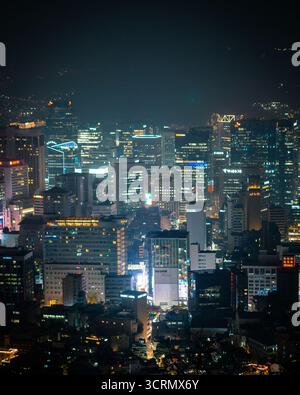 Nächtlicher Blick vom Namsan Tower über Myeongdong, Seoul, wo helle Stadtlichter aus dem geschäftigen Zentrum unter einem klaren, leuchtenden Himmel leuchten. Stockfoto