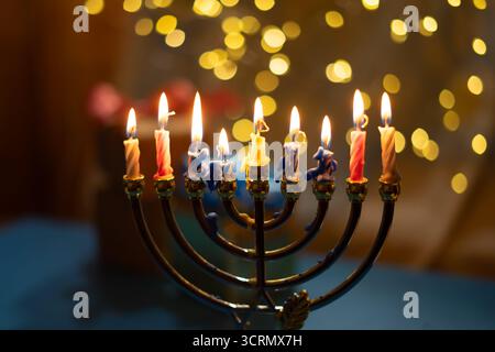 Eine Menora mit neun zündeten Kerzen vor einem sanften, leuchtenden Bokeh-Hintergrund, die Wärme und Frieden zur Feier von Hanukka weckt. Selektiver Fokus. Stockfoto