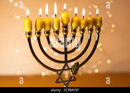 Eine Menora mit neun zündeten Kerzen vor einem sanften, leuchtenden Bokeh-Hintergrund, die Wärme und Frieden zur Feier von Hanukka weckt. Selektiver Fokus. Stockfoto