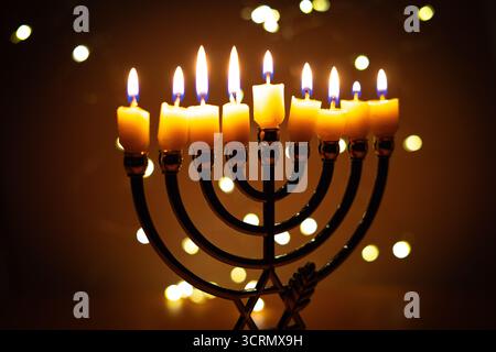 Eine Menora mit neun zündeten Kerzen vor einem sanften, leuchtenden Bokeh-Hintergrund, die Wärme und Frieden zur Feier von Hanukka weckt. Selektiver Fokus. Stockfoto