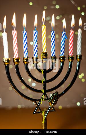 Eine Menora mit neun zündeten Kerzen vor einem sanften, leuchtenden Bokeh-Hintergrund, die Wärme und Frieden zur Feier von Hanukka weckt. Selektiver Fokus. Stockfoto