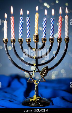 Eine Menora mit neun zündeten Kerzen vor einem sanften, leuchtenden Bokeh-Hintergrund, die Wärme und Frieden zur Feier von Hanukka weckt. Selektiver Fokus. Stockfoto