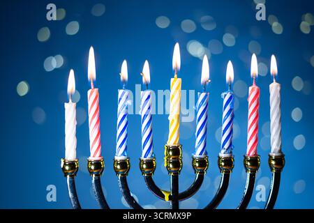 Eine Menora mit neun zündeten Kerzen vor einem sanften, leuchtenden Bokeh-Hintergrund, die Wärme und Frieden zur Feier von Hanukka weckt. Selektiver Fokus. Stockfoto