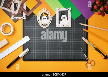 Flatlay mit Halloween-Motiven. Farbiges Papier, Schere, Lineal, Klebeband, Bleistifte, Schneider auf gelbem Hintergrund. Platz für Ihren Text. Stockfoto