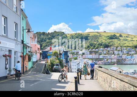 Im Sommer erkunden Menschen das Dorf Kingswear mit Blick über den Fluss Dart zu den farbenfrohen Hügelhäusern von Dartmouth, Devon England, Großbritannien Stockfoto