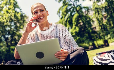 Digitale Nomaden Lifestyle, Frau, die an Laptop und Smartphone im Park arbeitet Stockfoto