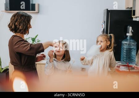 Mutter macht Zuckerwatte, während Töchter ihre Zeit genießen und miteinander verbringen Stockfoto