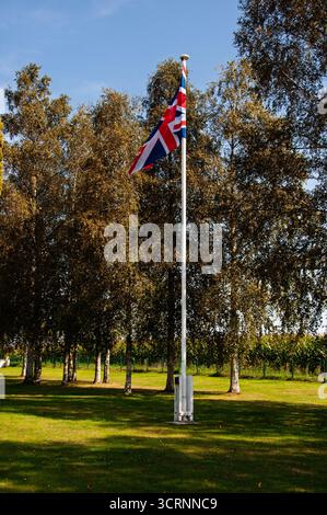 Der Union Jack fliegt hoch auf einem Pol und symbolisiert die britische Präsenz oder das Gedenken an diesem Ort. Stockfoto