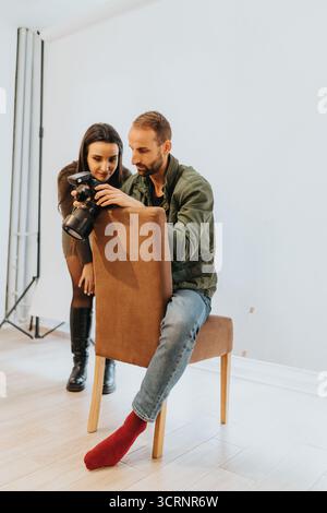 Fotograf und Frau, die die Kamera im Innenstudio zu Hause überprüfen Stockfoto