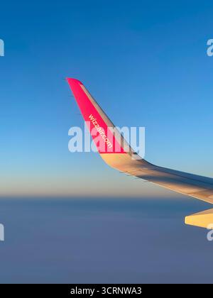 Der Blick aus dem Flugzeugfenster zeigt Wizz Air Wingtip vor einem ruhigen Himmel, der die ruhige Schönheit von Flug- und Budget-Reise-Branding einfängt Stockfoto