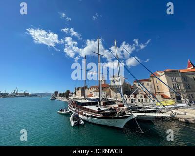 Segelyacht im Hafen von Trogir, Kroatien, mit historischen Altstadtgebäuden und Kirchturm unter einem klaren blauen Adriahimmel Stockfoto