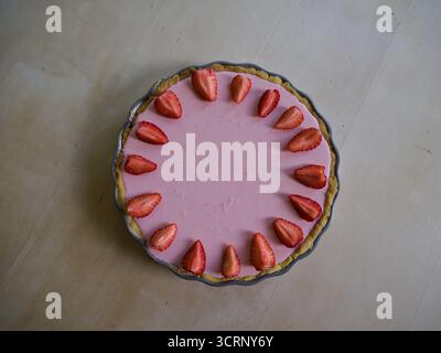 Blick von oben auf Erdbeertorte mit frischen Erdbeeren in Vintage-Keramikschale auf rustikalem Holztisch Stockfoto