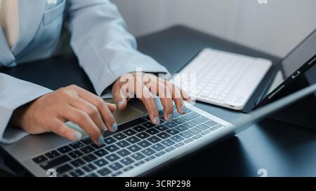 Nahaufnahme einer Geschäftsfrau, die auf einem Laptop mit Tablet und drahtloser Tastatur auf dem Schreibtisch schreibt, Konzept eines modernen Büros, Fernarbeit und digitaler Technologie wo Stockfoto