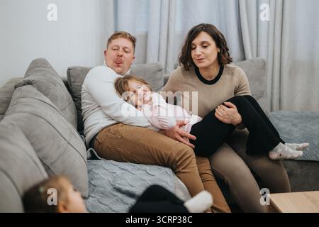 Glückliche Familie, die auf einer gemütlichen Wohnzimmercouch eine schöne Zeit miteinander verbringen kann Stockfoto