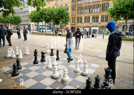 Spielen auf einem riesigen Schachbrett auf dem Platz vor dem PINC College und der Zentralbibliothek, Leeds, Großbritannien Stockfoto