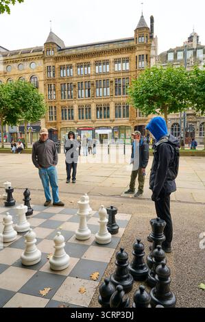 Spielen auf einem riesigen Schachbrett auf dem Platz vor dem PINC College und der Zentralbibliothek, Leeds, Großbritannien Stockfoto