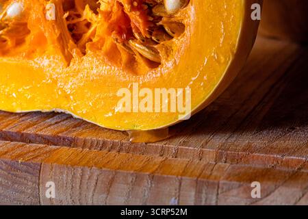 Makronaht von frischem Butternusskürbis, der Samen zeigt, eingebettet in leuchtendem Orangenfleisch und faseriger Textur. Detaillierte Lebensmittelfotografie, die nat hervorhebt Stockfoto