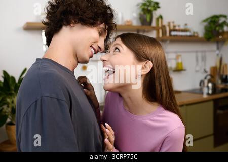 Ein junges Paar teilt Lachen und Liebe in ihrer modernen Wohnung und umschließt sich gegenseitig. Stockfoto