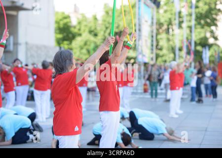 Eine Gruppe von Seniorinnen verwendet farbenfrohe Basketball in einer koordinierten Outdoor-Übung, die Balance, Mobilität und Inklusion als Teil des Gemeinschafts-Wellness fördert Stockfoto