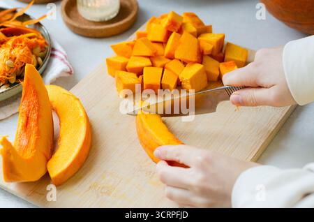 Nahaufnahme einer Frau, die Kürbis für Herbstrezepte in Würfel schneidet Stockfoto