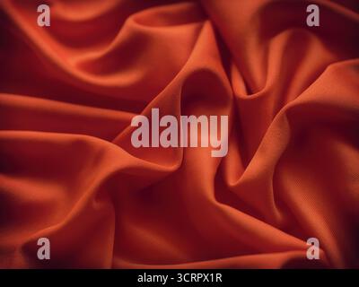 Ein rötlich-oranger Hintergrund mit faltiger Textur. Nahaufnahme. Stockfoto