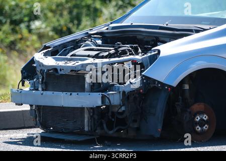Beschädigtes Fahrzeug ohne vorderen Stoßfänger und Vorderrad, das nach einem Unfall oder einem mechanischen Defekt auf der Straße geparkt wurde. Stockfoto