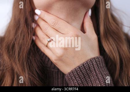 Junge Frau, die den Hals berührt und an Halsschmerzen leidet. Erkältungs- oder Grippesymptom mit Schmerzen in den Mandeln. Gesundheitsproblem und Saisonkrankheitskonzept. Stockfoto