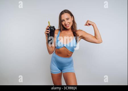Frau in blauem Workout, die sich mit einer Shaker-Flasche biegt. Stockfoto