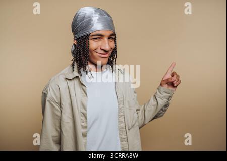 Junge Person mit einer durag, die zur Seite zeigt, neutraler Hintergrund. Stockfoto