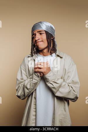 Junger Mann mit geflochtenen Haaren, der ein durag und ein lässiges Hemd trägt. Stockfoto