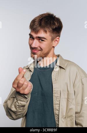 Junger Mann, der eine Fingerherz-Geste macht, lächelt. Stockfoto