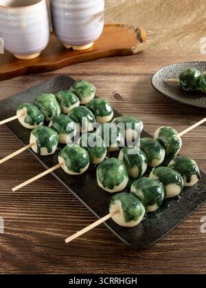 Einige Dancos sind auf einem schwarzen Teller, begleitet von Matcha-Sauce. Auf der Rückseite sehen wir japanisches Silbergras. Stockfoto